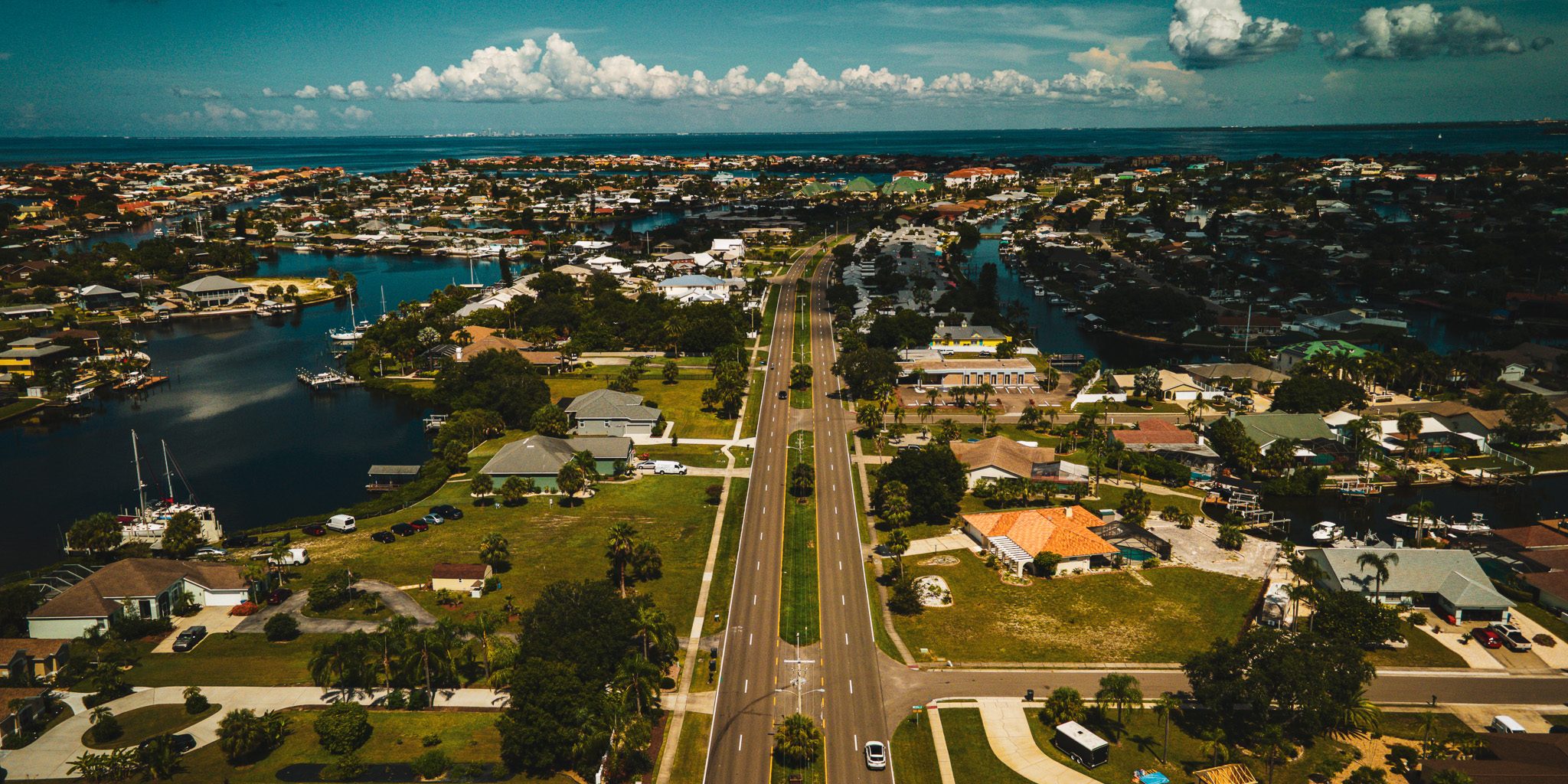Aerial view over Apollo Beach canal homes and boat docks, with Tampa Bay on the horizon