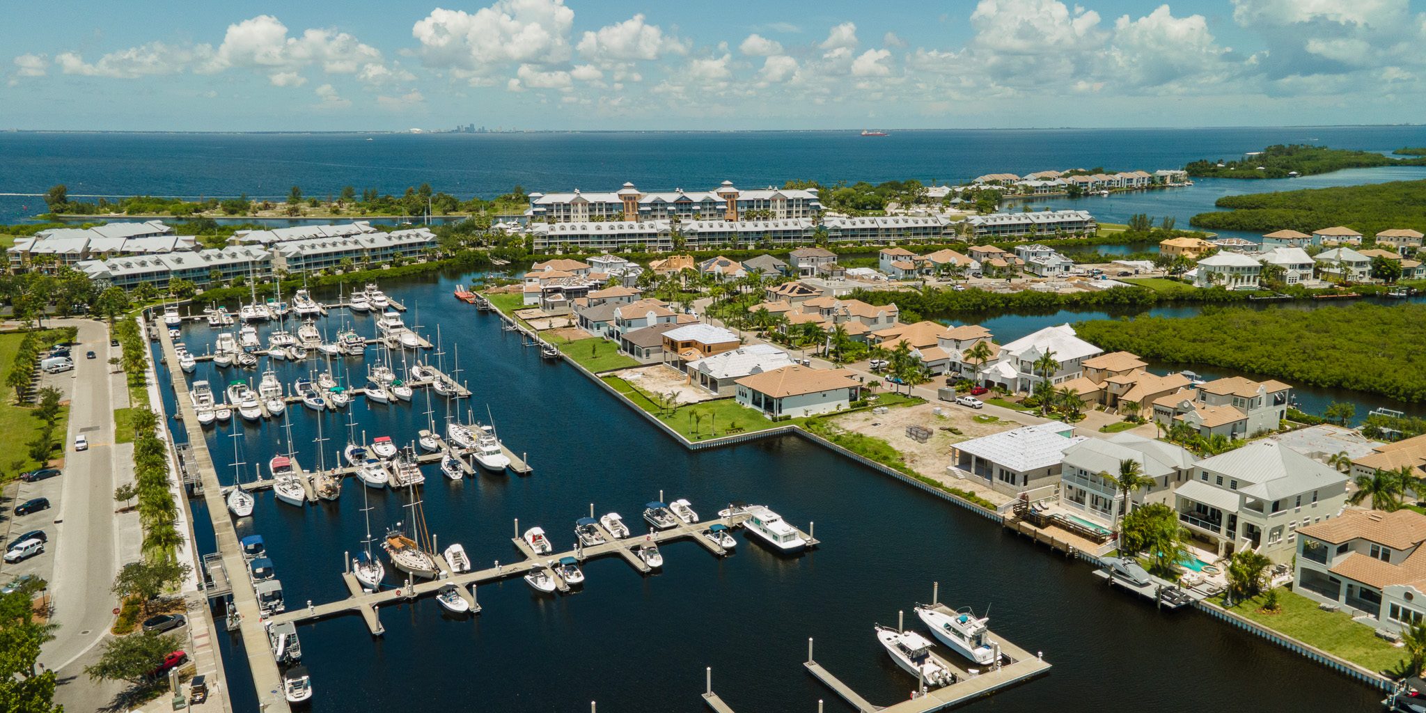 Aerial view of a marina and new waterfront homes near the mouth of the Little Manatee River in Ruskin, with Tampa Bay and the Tampa skyline behind