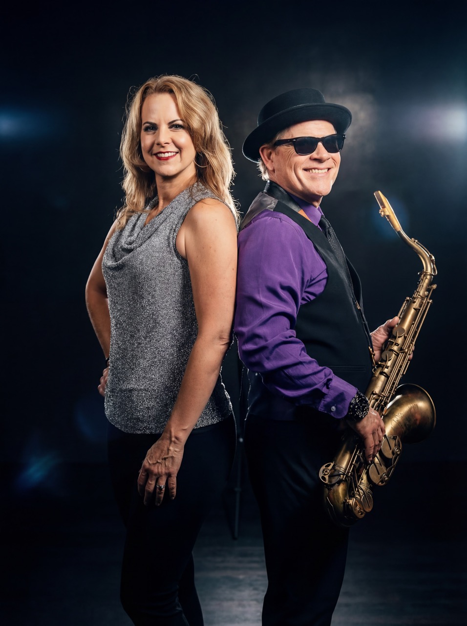 Dave and Corena standing back to back in a promotional portrait