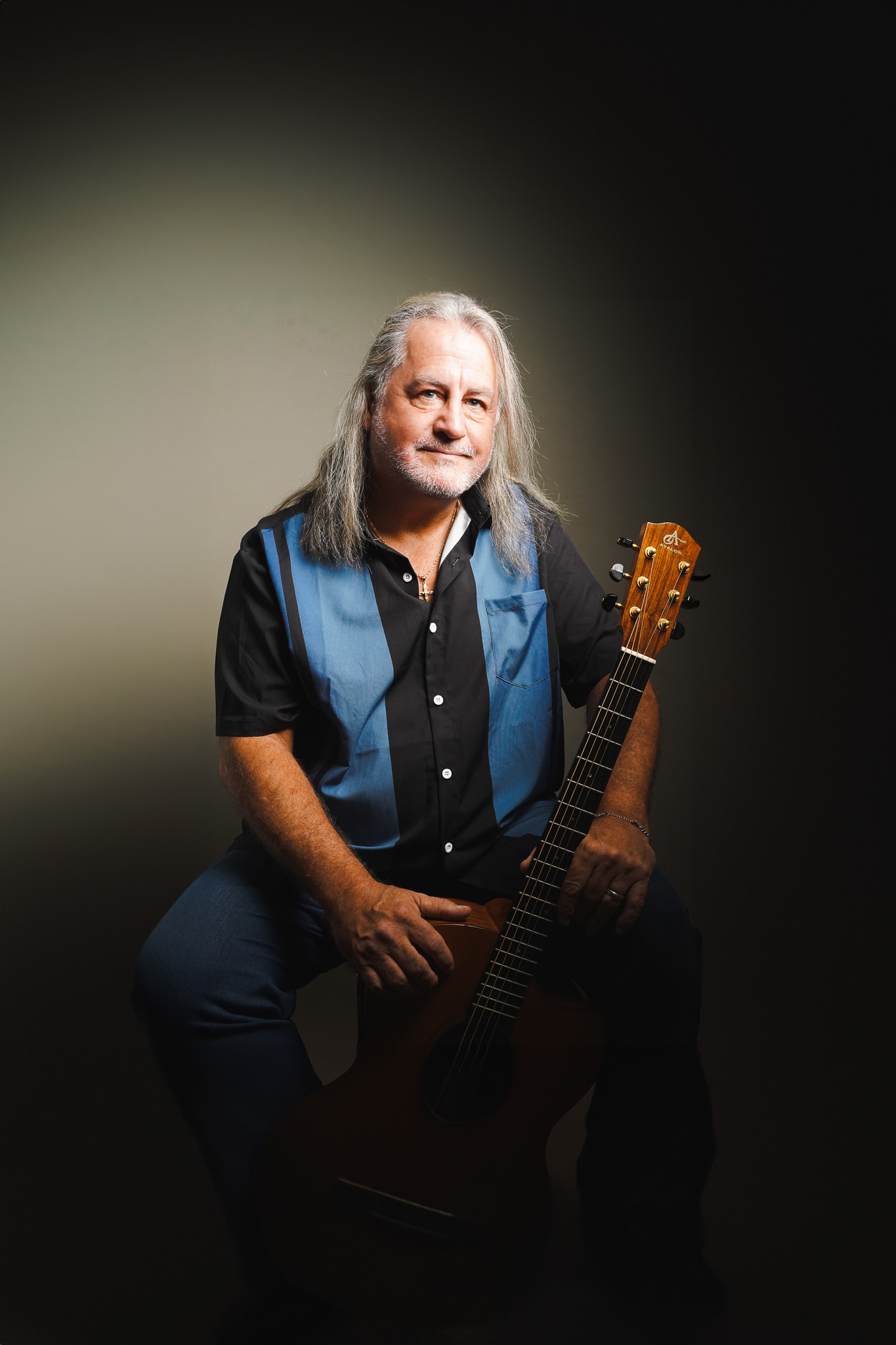 Donnie Ray Reynolds — seated studio portrait with acoustic guitar