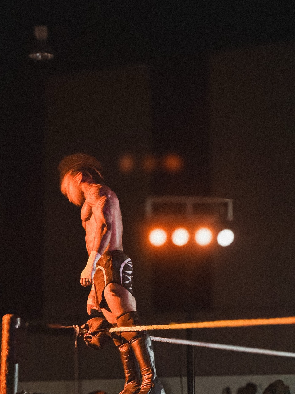 Silhouette of a wrestler on the turnbuckle during a live match