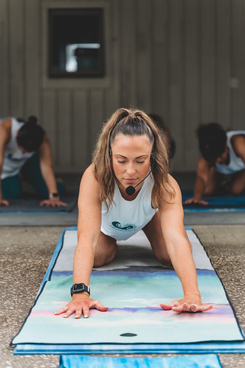 Abundance Movement instructor holding a plank with a headset mic
