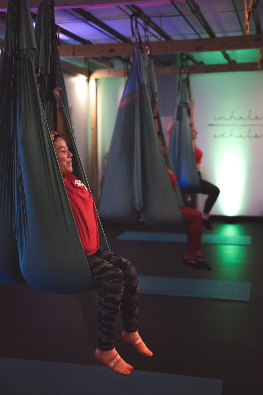Aerial Pilates in a green silk hammock under magenta and green stage lighting